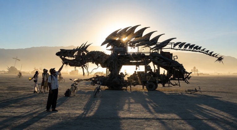 Koda petting a dragon art car at Burning Man